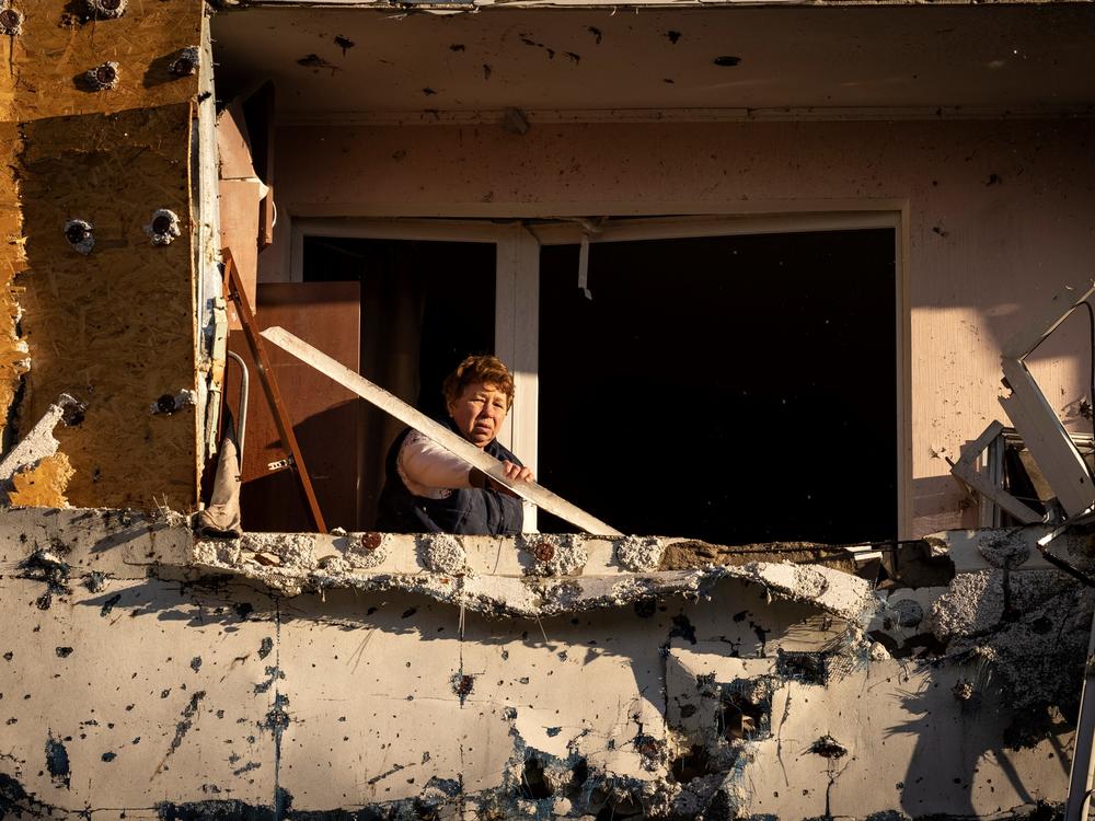 A resident cleans her balcony in an apartment building damaged by shelling in Kyiv on Tuesday.