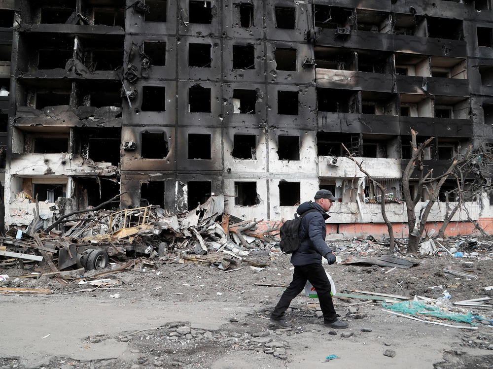 A man walks on Thursday near a block of flats destroyed in the besieged Ukrainian city of Mariupol.