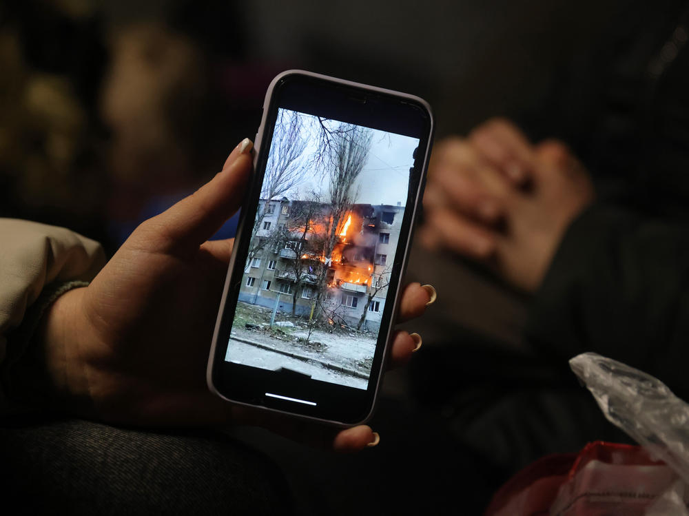 Iryna Holoshchapova, a Ukrainian refugee who fled the embattled city of Mykolaiv, shows a video on her smartphone of an apartment block on fire following a Russian attack.