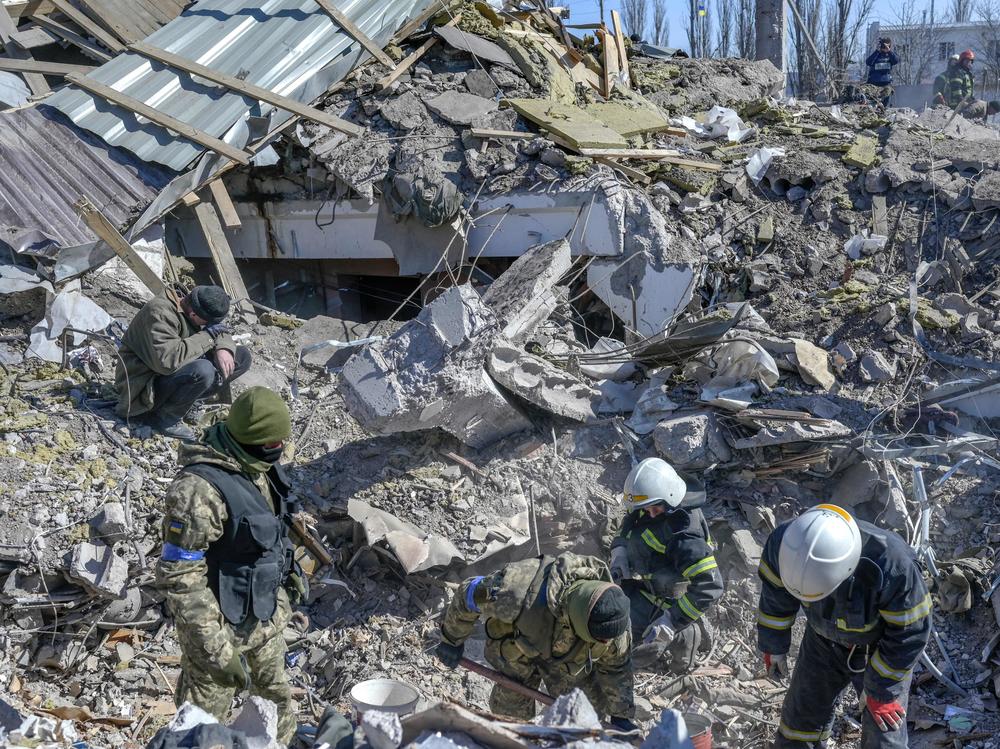 Ukrainian soldiers and rescue officers search for bodies in the debris at a military school in Mykolaiv on Saturday. Russian rockets hit the school the day before.