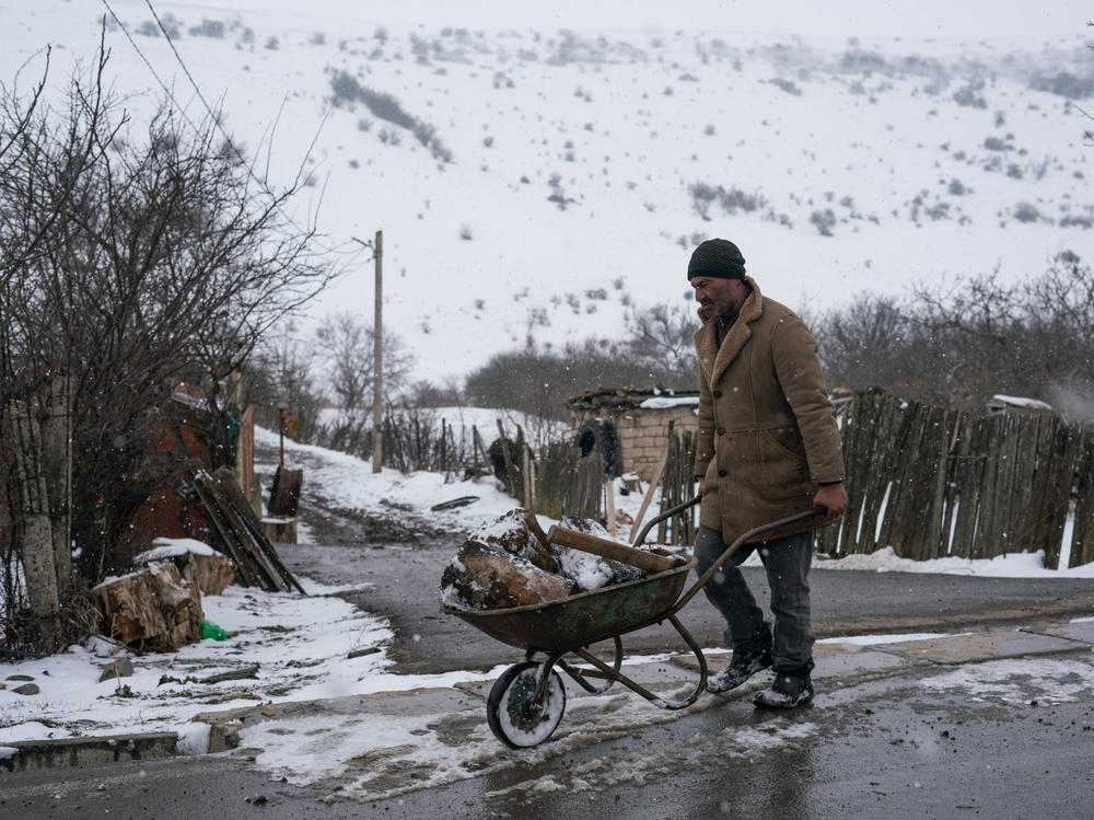 A man pushes a wheelbarrow full of wood on a street in Khurvaleti, a village split in two by the boundary of South Ossetia.