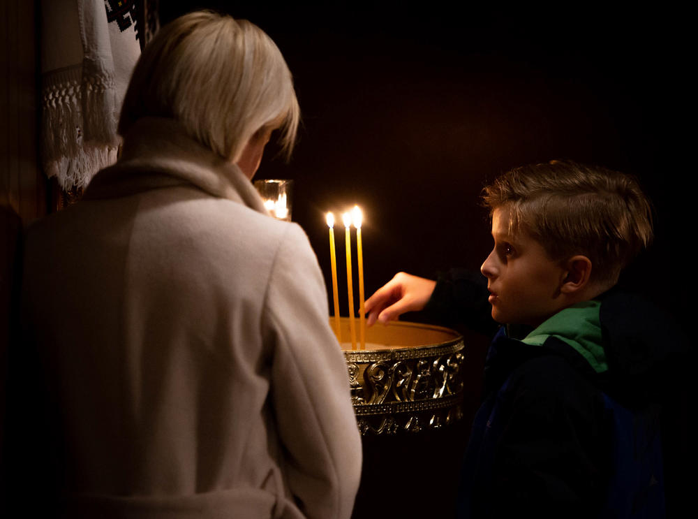 <strong>Feb. 25:</strong> Nataliya Ovod of St. Louis, Missouri, lights candles alongside her son, Antony, at St. Mary's Assumption Ukrainian Church in south St. Louis County. Russian forces had attacked Kyiv earlier in the day.