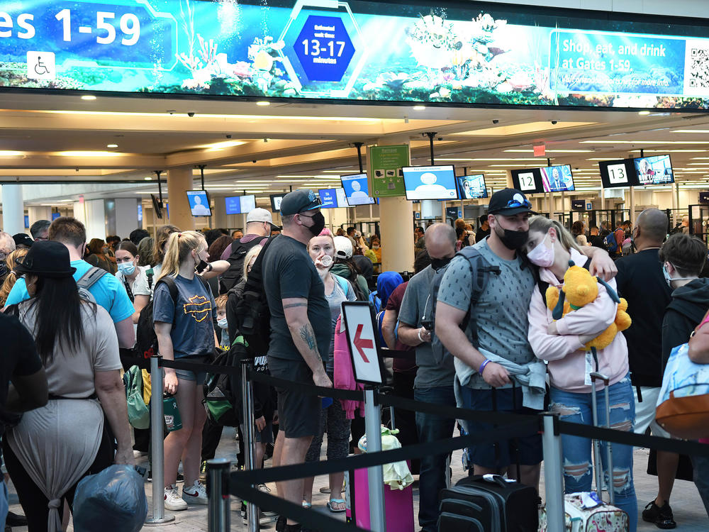 Spring break passengers wait in a TSA security line at Orlando International Airport. While COVID-19 face masks are still required, crowds have increased over last year.