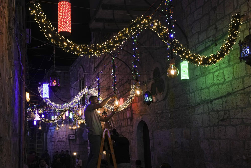 <strong>Jerusalem, Israel:</strong> A Palestinian man hangs decorative lights in preparation for the holy Muslim month of Ramadan.
