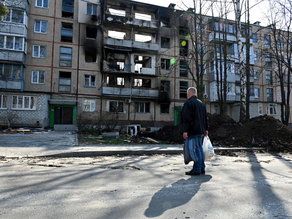 A man looks at a five-story residential buildings in the Ukrainian city of Kharkiv, on April 10, 2022.