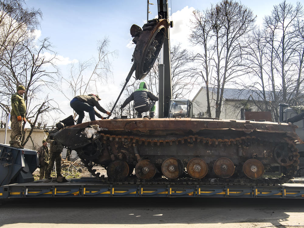 Workers remove a destroyed Russian military tank from the road near Andriivka, a village close to Kyiv, Ukraine, on Monday.