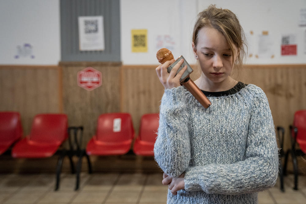 Sofia Kotlyarova holds a microphone as she prepares to sing the Ukrainian national anthem in one of the waiting rooms at Gara de Nord railway station. She came to Romania with her mother, Ira, grandmother, Lydia Melnik and the family dog, Fenya.