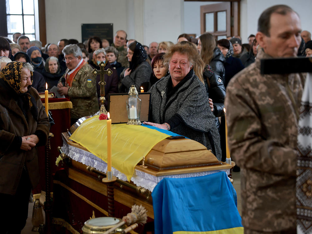 A Ukrainian woman,  Maria Korechko, touches the flag-draped casket of her son, Ukrainian soldier Andriy Zagornyakon, during his funeral on April 10, 2022 in Kamianka-Buzka, Ukraine.