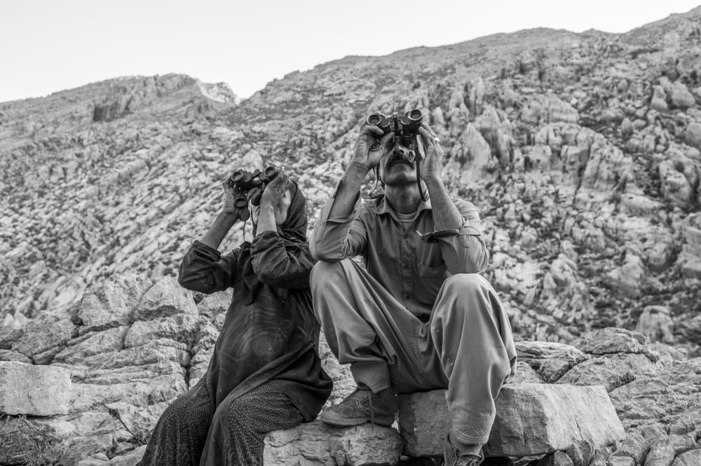 Rostam, 40, and Farzaneh, 37. She was seven months pregnant and awaiting the birth of their sixth child when this photo was made in June 2021. The couple use binoculars to keep an eye on their 95 goats — and keep an eye out for wild animals that could threaten them.