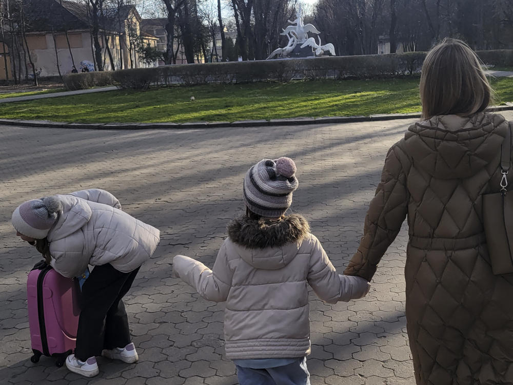 Kateryna Kltsova, right, with her two daughters Nadia, 7, center, and Maria, 11, left, with their new pink suitcase in a park in Lviv.