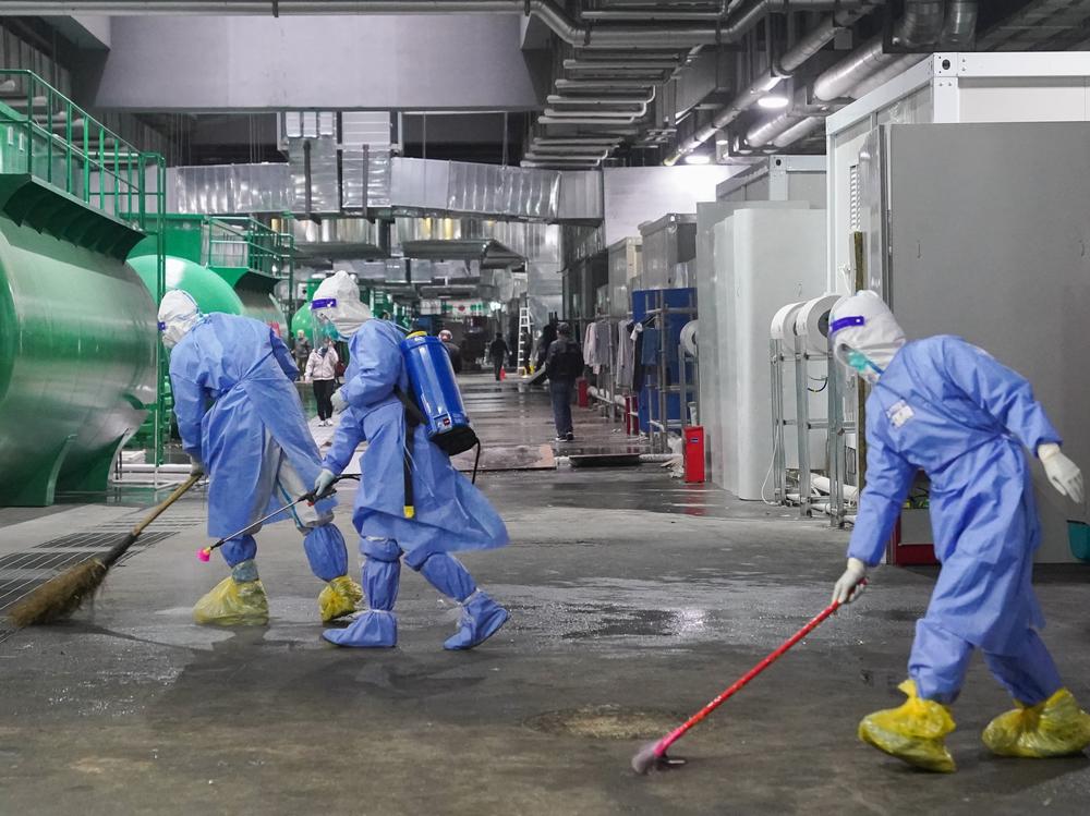 Workers clean and disinfect the floor at the National Exhibition and Convention Center NECC, the largest makeshift hospital, in Shanghai. Many jobs in these temporary facilities are drawn from the pool of unemployed migrant workers.