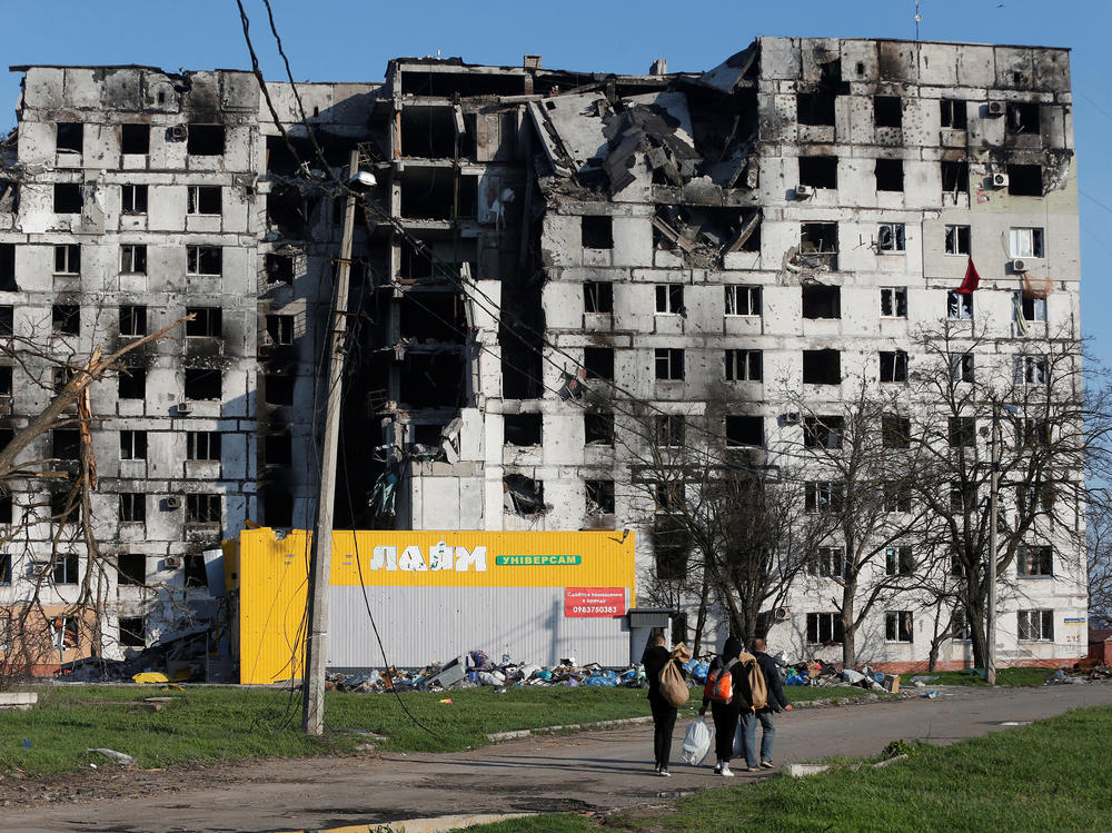 Residents walk past an apartment building on Wednesday in Mariupol, Ukraine, destroyed during the war with Russia.