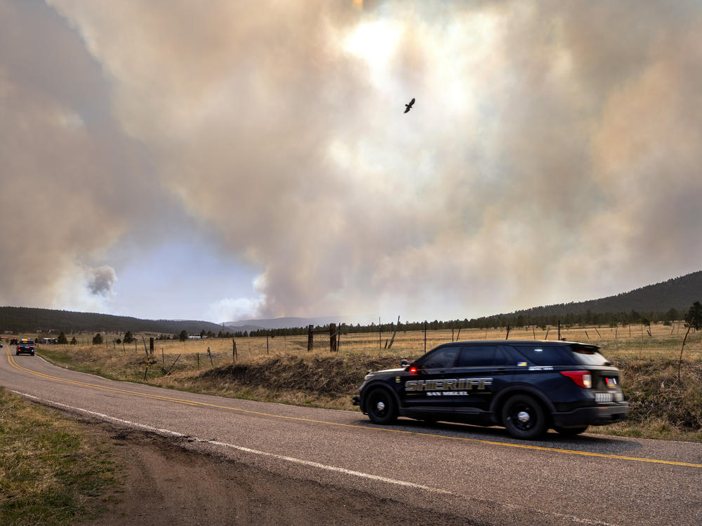 San Miguel County Sheriff's Officers patrol N.M. 94 near Penasco Blanco, N.M., as the Calf Fire burns nearby on Friday.