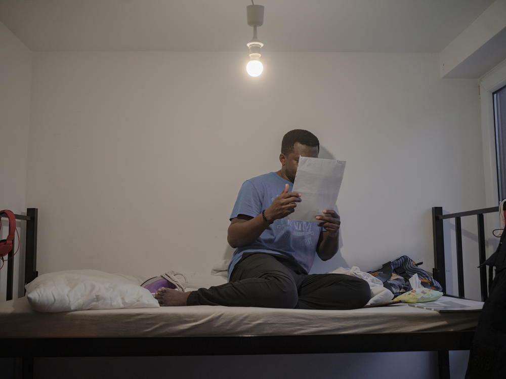 Tony reads a paper on a bed at the home.