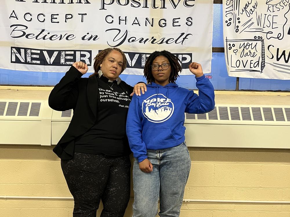 Rev. Denise O. Walden-Glenn and Alia Williams each raise a fist— a symbol of solidarity and Black power— at the VOICE office in Buffalo, New York.