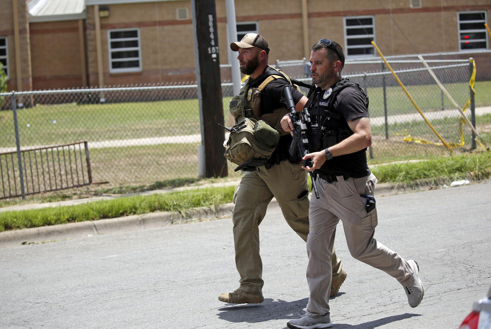 Police walk near Robb Elementary School following a shooting.