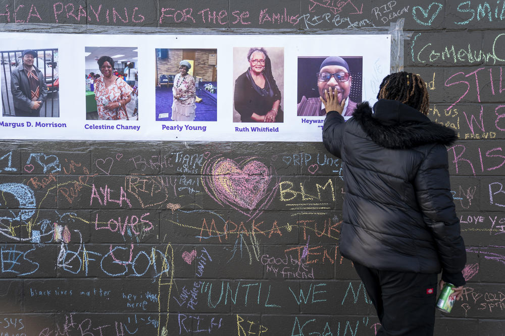 Kimberly Johnson, of Buffalo, places her hand on a photo of the late Hayward Patterson, at makeshift memorial across the street from the scene of a mass shooting at Tops Friendly Market at Jefferson Avenue and Riley Street on Thursday, May 19, 2022 in Buffalo, NY. T