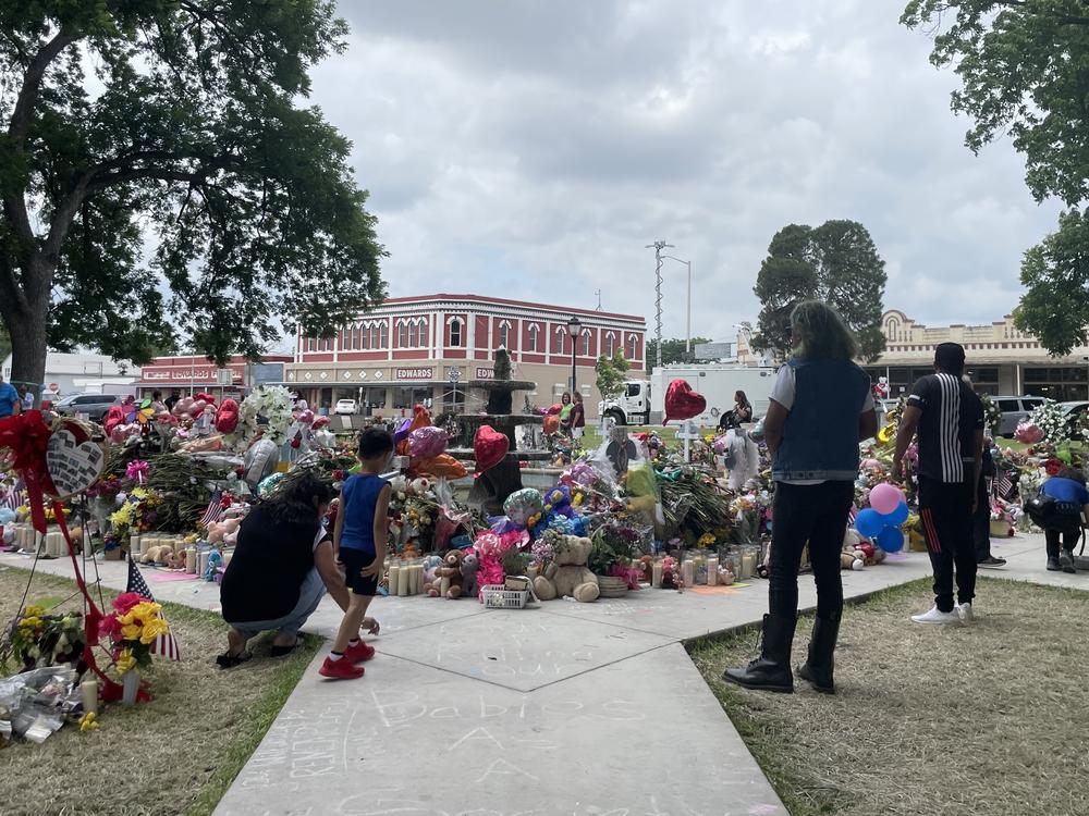 Amy Nuñez, Israel Sanchez and others pay respect to the school shooting victims at a makeshift memorial in the center of Uvalde on Tuesday.