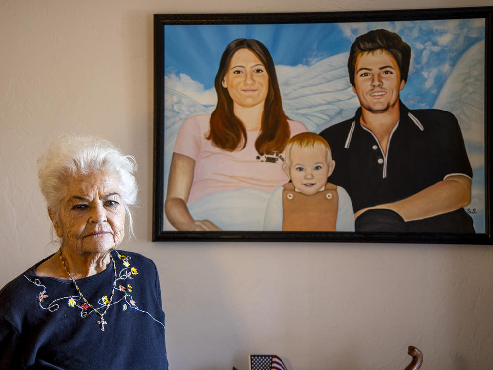 Donna Casasanta poses in front of a painting showing her late son, Harold Dean Clouse Jr., with Clouse's wife, Tina Gail Linn, and their daughter, Holly Marie Clouse, at Casasanta's Edgewater, Fla., home on Friday, Jan. 14, 2022.
