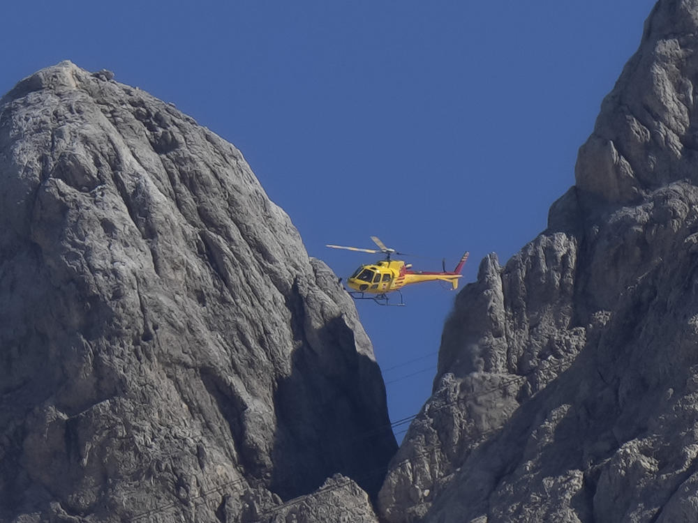 A rescue helicopter hovers over the Punta Rocca glacier near Canazei, in the Italian Alps in northern Italy, Monday, July 4, 2022.