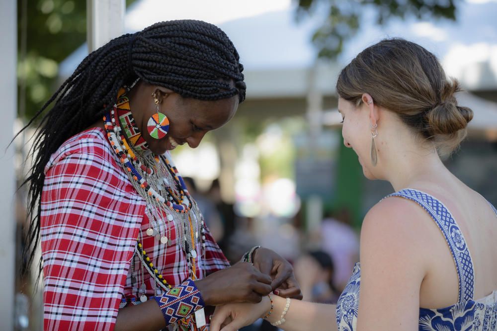 Simaloi Saitoti, a Maasai bead artist from Kenya, ties a bracelet around a visitor's wrist. Saitoti is one of many artisans around the world showcasing their works at the Smithsonian Folklife Festival.