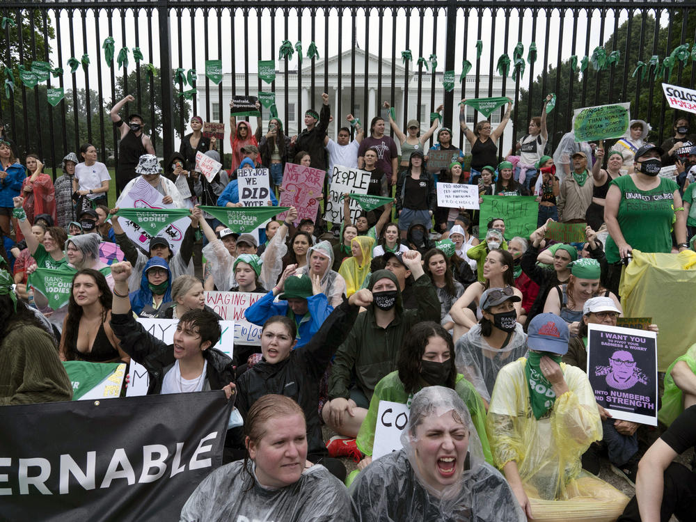 Abortion-rights demonstrators shout slogans after tying green flags to the fence in front of the White House during a protest to pressure the Biden administration to act and protect abortion rights on Saturday.