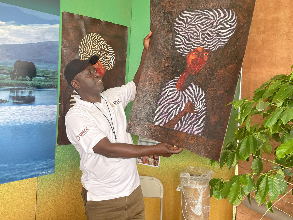 Fred Mutebi, a Ugandan artist, holds up one of his paintings, which uses traditional Ugandan barkcloth as a canvas.