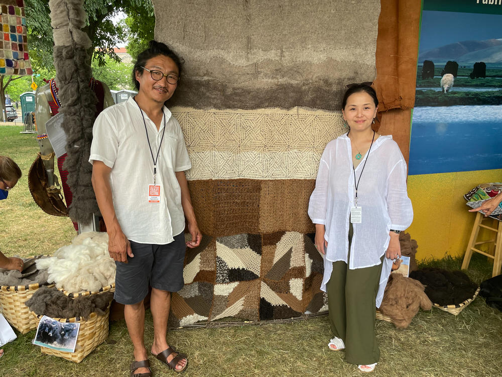 Mongolian couple Enkhbold Togmidshiirev (left) and Munguntsetseg Lkhagvasuren stand in front of their first collaborative piece of artwork, a felt tapestry made from the hairs of five different animals.