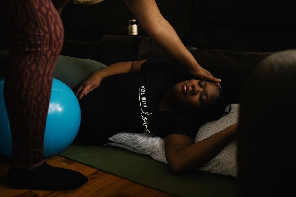 Home visits are a regular part of Kemp's daily routine. Here, she guides Aireonna Reese, who had a difficult labor with a previous pregnancy, through a series of prenatal stretches during the early stages of labor.