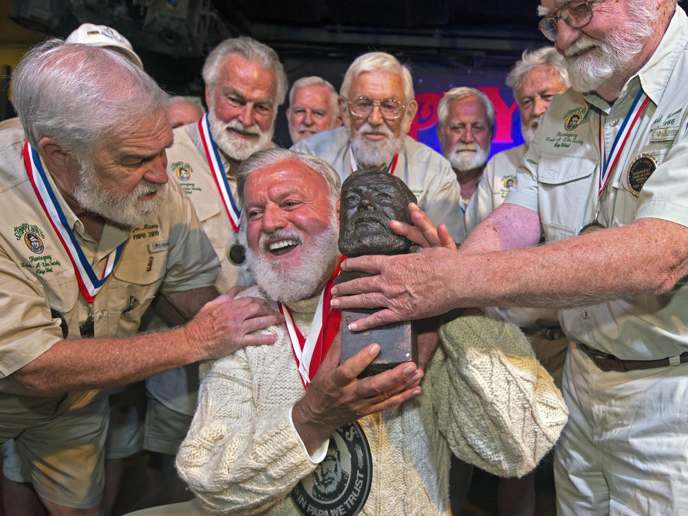 Jon Auvil, center, receives an Ernest Hemingway bust and congratulations after he won the 2022 Hemingway Look-Alike Contest at Sloppy Joe's Bar in Key West, Fla. Left of Auvil is Joe Maxey, the 2019 winner, and at right is Fred Johnson, who won in 1986. It was Auvil's eighth attempt in the annual contest.