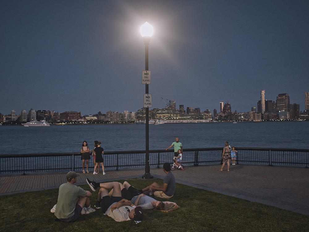 People spend time at the park at dusk during a summer heat wave in Hoboken, N.J., on July 21, 2022.