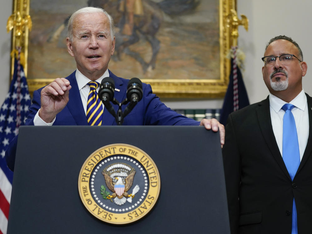 President Joe Biden speaks about student loan debt forgiveness at the White House on Wednesday, with U.S. Education Secretary Miguel Cardona by his side.