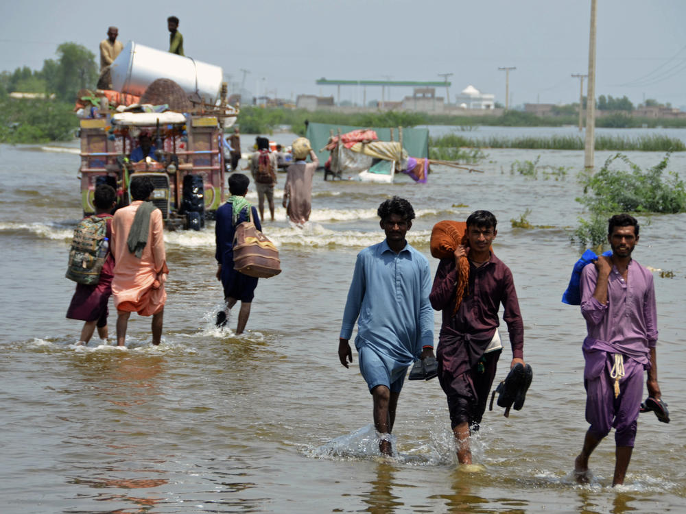 People wade through a flooded area in Pakistan, that has been dealing with what people are calling 