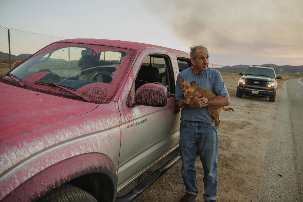Rick Fitzpatrick holds a dog after evacuating from the Fairview Fire on Monday near Hemet, Calif.