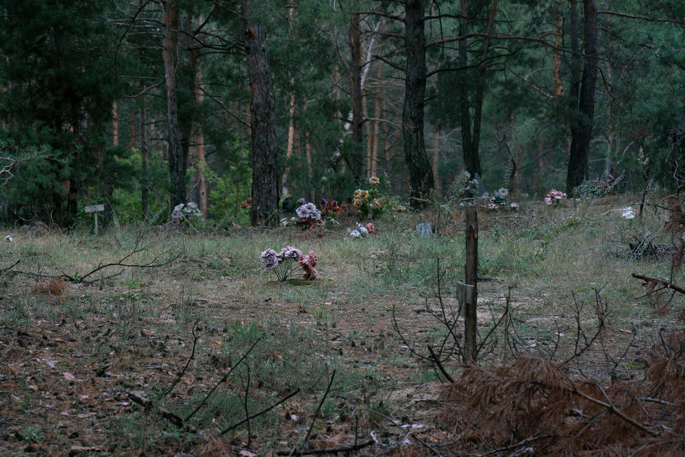 Many of the individual graves at the mass grave site are decorated with plastic flowers, or draped in cloth.