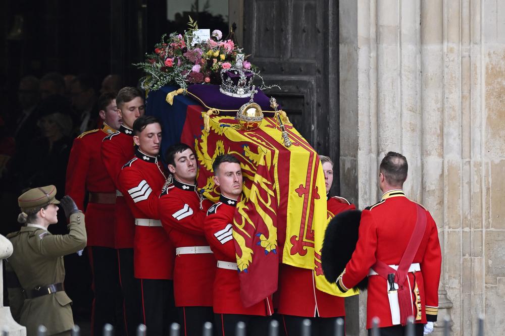 The Bearer Party of The Queen's Company, 1st Battalion Grenadier Guards carries the coffin of Queen Elizabeth II, draped in a Royal Standard and adorned with the Imperial State Crown and the Sovereign's orb and sceptre from the Abbey at the State Funeral Service for Britain's Queen Elizabeth II at Westminster Abbey on Monday.