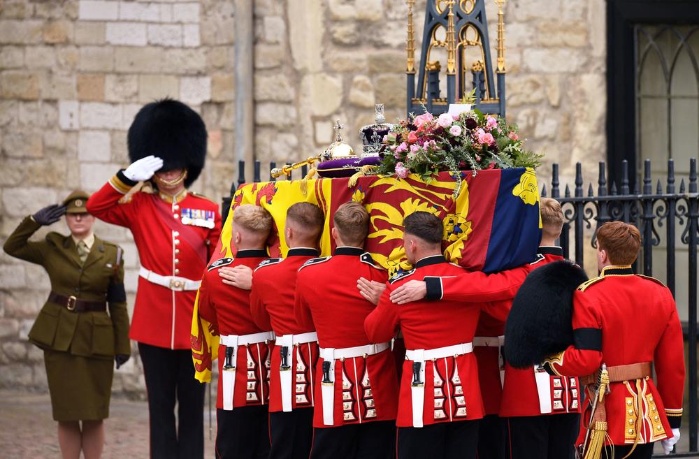 The coffin of Queen Elizabeth II, draped in a Royal Standard and adorned with the Imperial State Crown and the Sovereign's orb and sceptre is taken into Westminster Abbey.