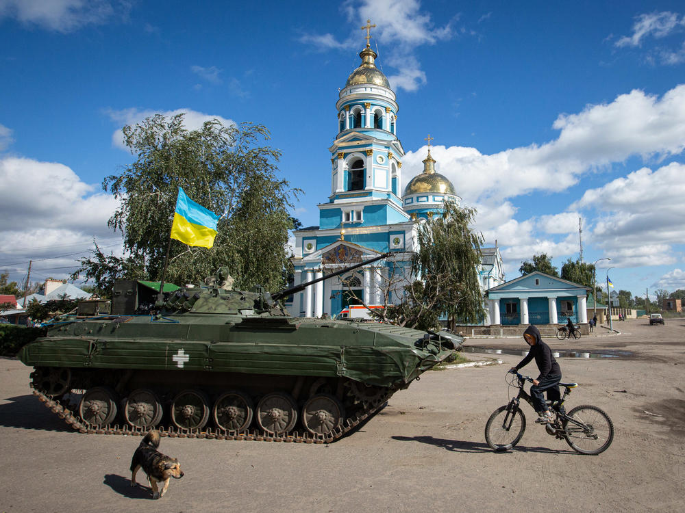 A boy rides a bicycle near an armored tank with a Ukrainian flag in the town of Izium, recently liberated by Ukrainian armed forces, in the Kharkiv region on Monday. Russian troops occupied Izium on April 1.
