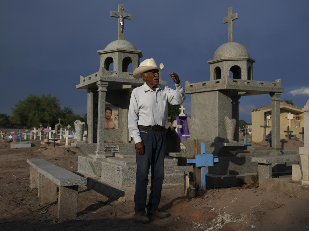 Guillermo Rojo, the father of slain water-defense leader Tomás, prays next to his tomb, decorated with a blue cross, at the cemetery in Potam, Mexico, Tuesday, Sept. 27, 2022.
