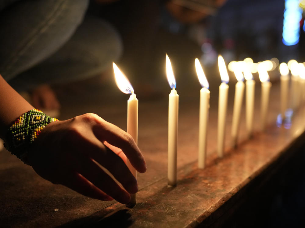 Activists light candles as they condemn the killing of Filipino journalist Percival Mabasa during a rally in Quezon, Philippines, Tuesday Oct. 4, 2022.