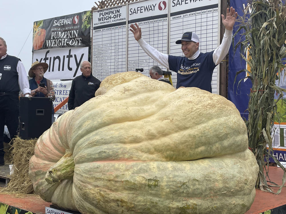 Travis Gienger from Anoka, Minn., stands behind his winning pumpkin at the 49th World Championship Pumpkin Weigh-Off in Half Moon Bay, Calif., on Monday.