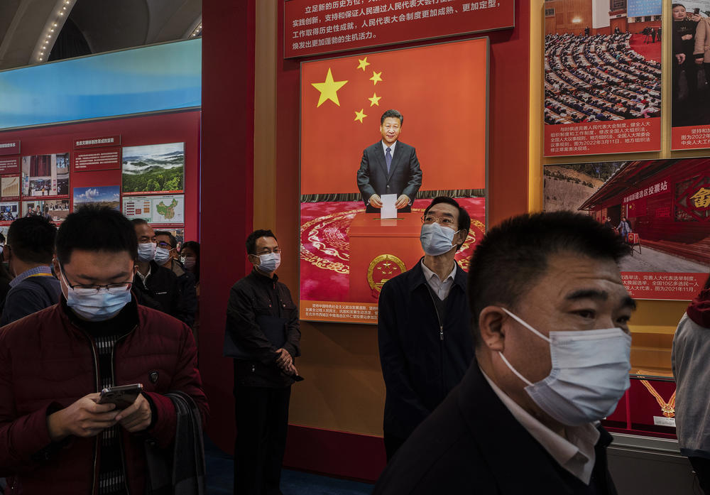 Party members walk by an image showing Chinese President Xi Jinping at an exhibition highlighting Xi's years as leader, as part of the upcoming 20th Party Congress, in Beijing on Wednesday. The ruling Communist Party of China will open its 20th Party Congress on Oct. 16 and Xi Jinping is widely expected to secure a third term in power.