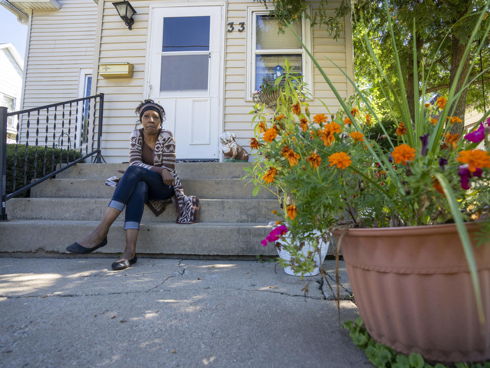 Laurie Thomas sits on the front step of her mother's home in Freeport, Illinois on Sept. 18, 2022. This past May, floodwaters rose to the first step and inundated the basement.
