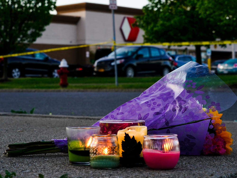 Flowers and candles lay outside the scene of a shooting at a supermarket, in Buffalo, N.Y., Sunday, May 15, 2022.