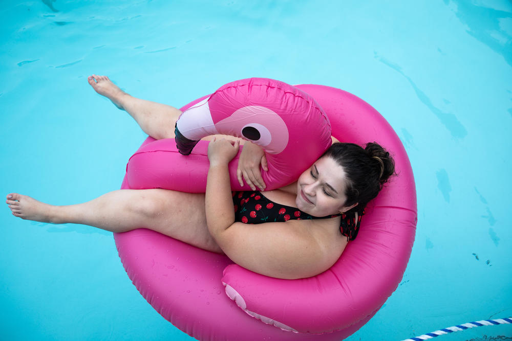 Anna Helmig, 26, hugs an inflatable flamingo in the pool at Camp Roundup.
