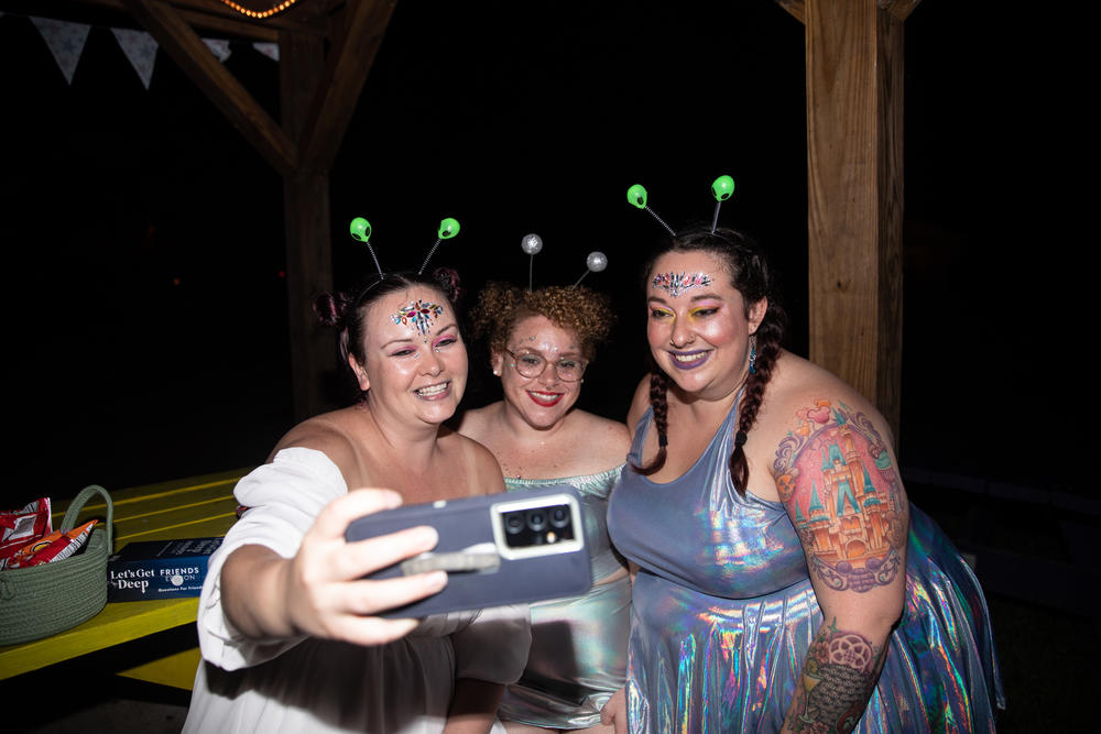 Friends Mary Yale, 31, Alleiah Keeley, 33, and Regina Sigafoos, 30, take a selfie during Camp Roundup's space-disco party.