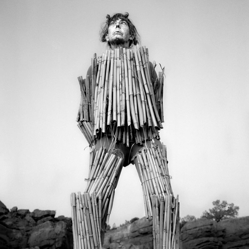 <em>Visible</em>, 2020. I took measurements of Marcia's body and cut dried bamboo from her garden to fit her as armor, or rather as a shelling. Here, she's standing on a giant boulder even though she's afraid of heights. The air is still. All we can hear are distant cars zooming by on nearby highways.