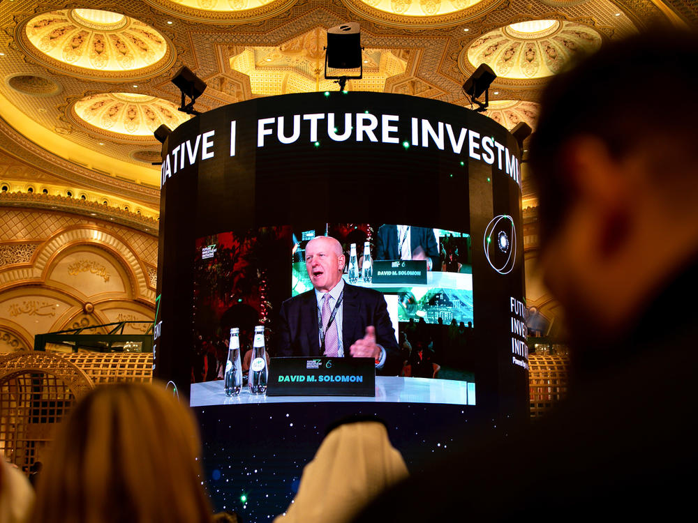 Attendees watch David Solomon, chief executive officer of Goldman Sachs & Co., on a screen as he speaks during a panel session at the Future Investment Initiative (FII) conference in Riyadh, Saudi Arabia, on Tuesday, Oct. 25, 2022.