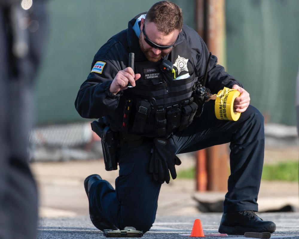 A Chicago police officer examines a Glock handgun found May 4 in the 8200 block of South Halsted Street where a 20-year-old man was shot and wounded. According to police records, the gun was equipped with an automatic switch and extended magazine. No one has been charged in that shooting.