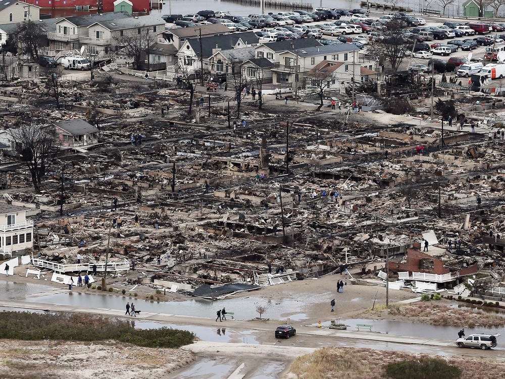 People walk near the remains of burned homes after Hurricane Sandy in the Breezy Point neighborhood of the Queens borough of New York City on Oct. 31, 2012. Over 50 homes were reportedly destroyed in a fire during the storm.